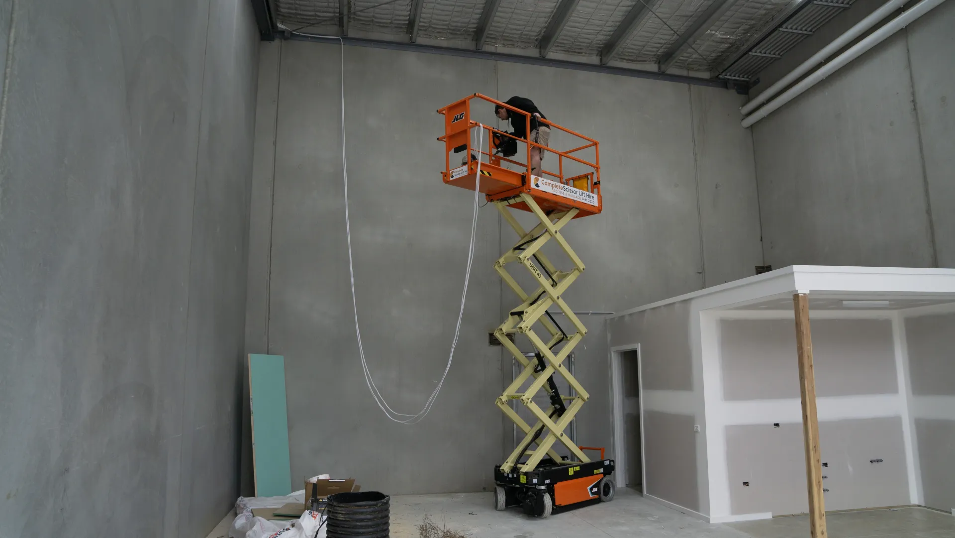 Orr Electrical electrician on a scissor lift wiring a new commercial building