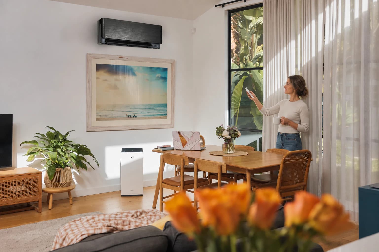 Woman adjusting an efficient reverse cycle split system with the remote in a bright living room